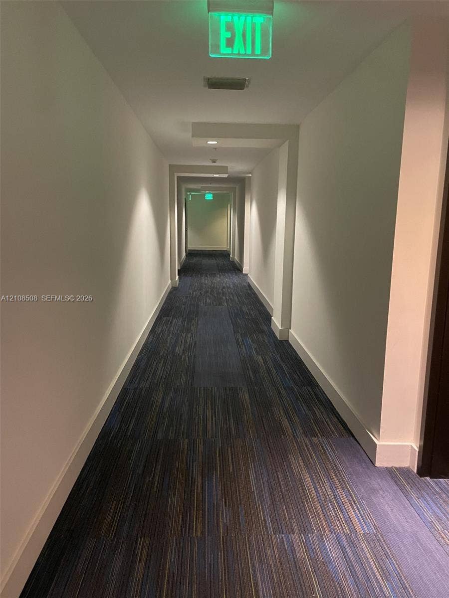 Hallway featuring recessed ceiling lighting, textured blue and brown carpet flooring, and architectural soffit details