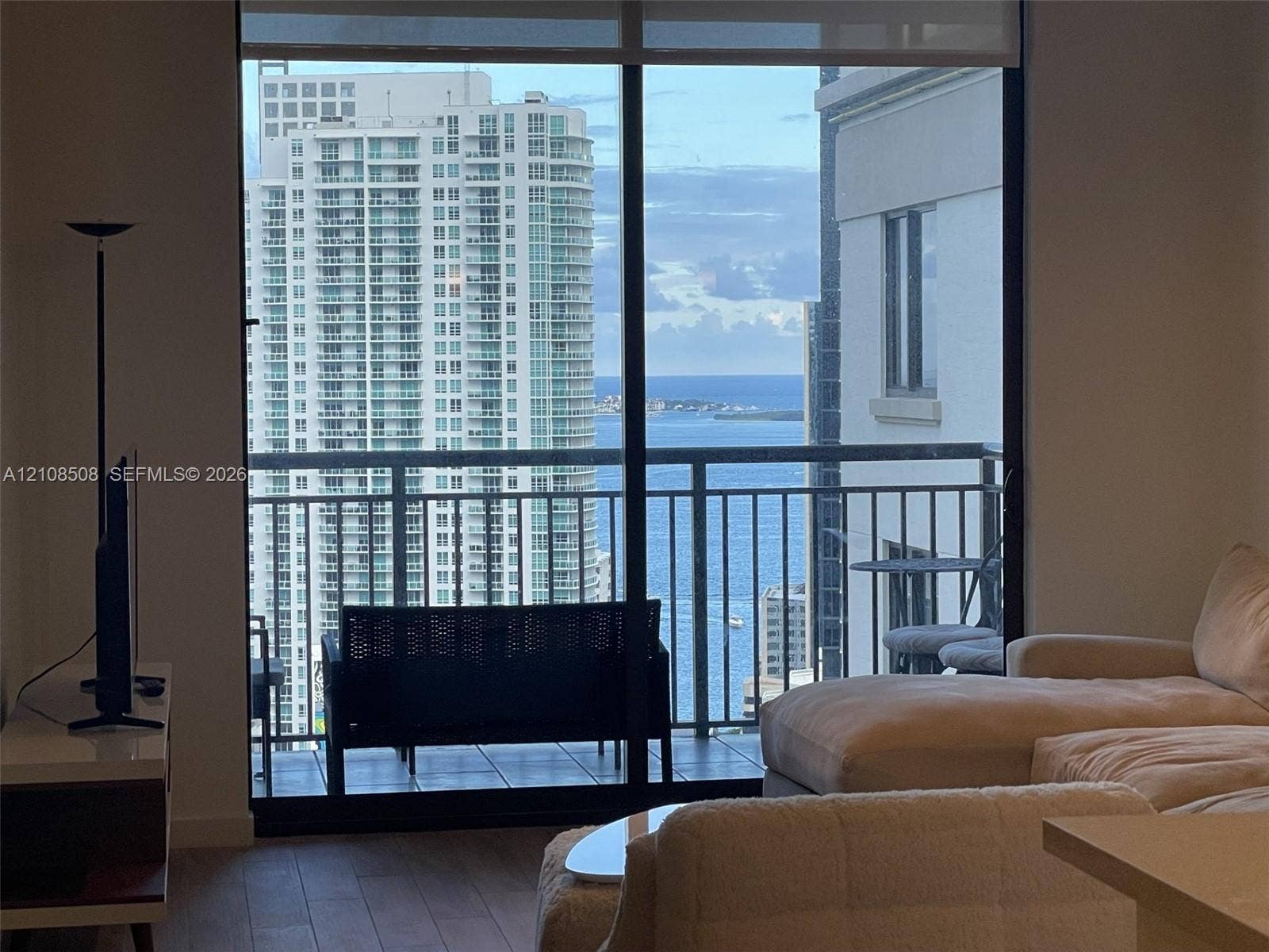 Floor-to-ceiling sliding glass door, private balcony with metal railing, and engineered wood-finish flooring