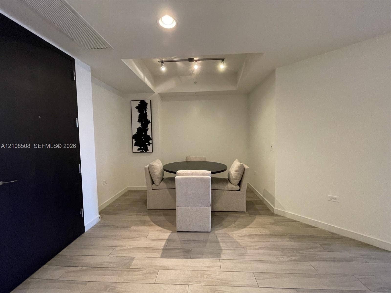 Interior space featuring wood-finish tile flooring, recessed ceiling lighting, a tray ceiling detail, and a matte black door