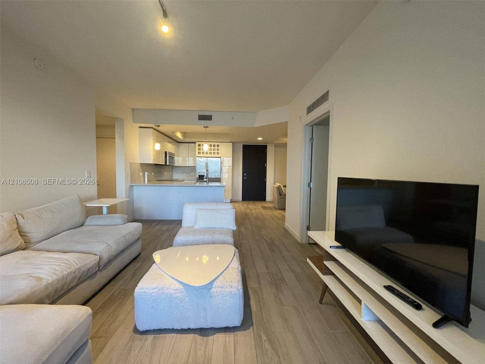 Open-concept interior featuring wood-finish flooring, white cabinetry, a breakfast bar, and recessed lighting