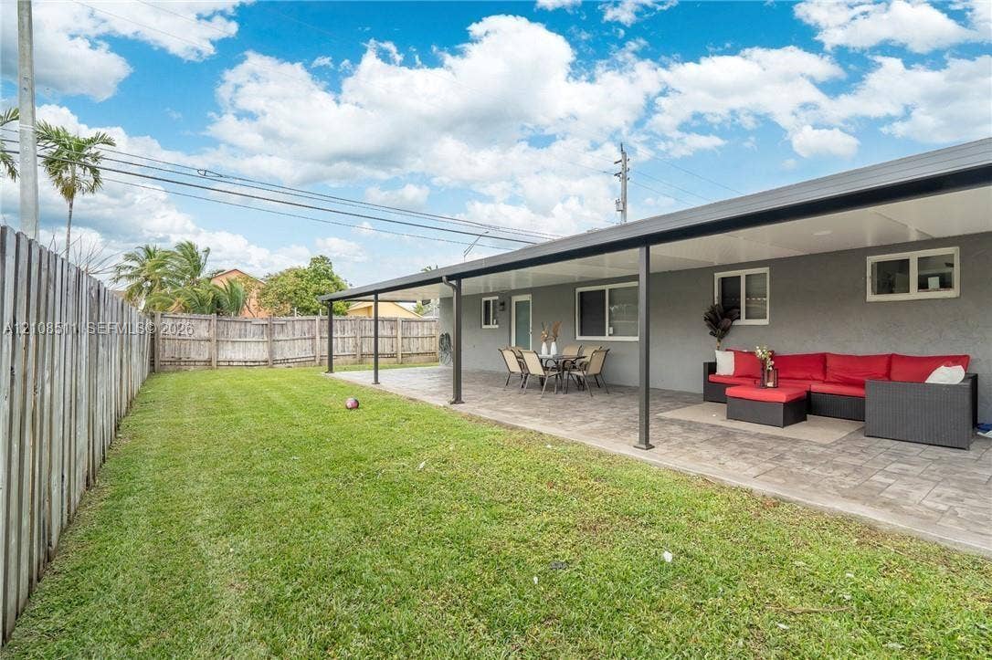 Miramar, Miramar, FL 33025 Expansive backyard featuring a manicured lawn, a paved patio, a full-length covered terrace, and perimeter wood fencing
