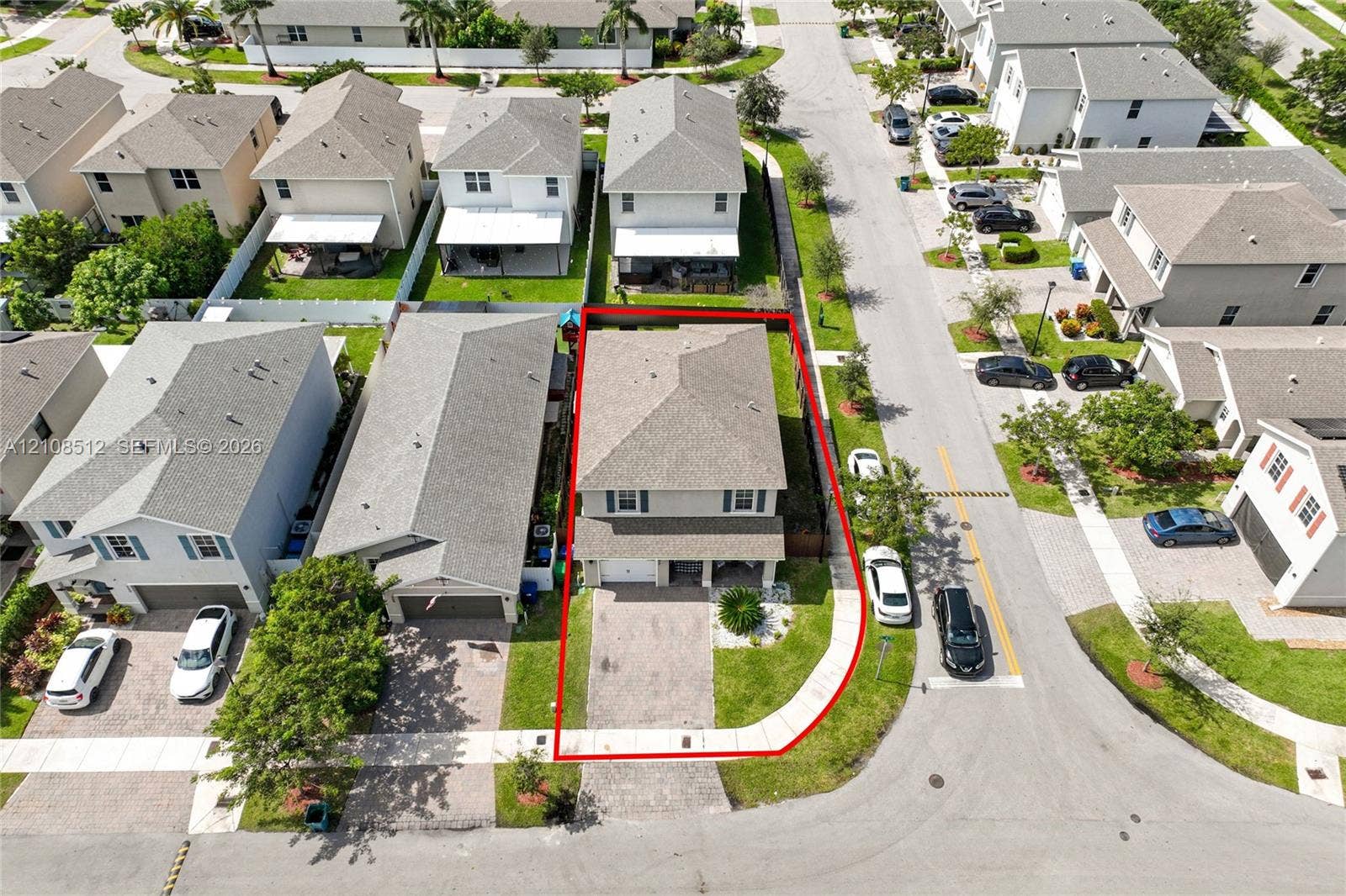 Two-story residence featuring a paved driveway, attached garage, shingled hip roof, and a corner lot configuration