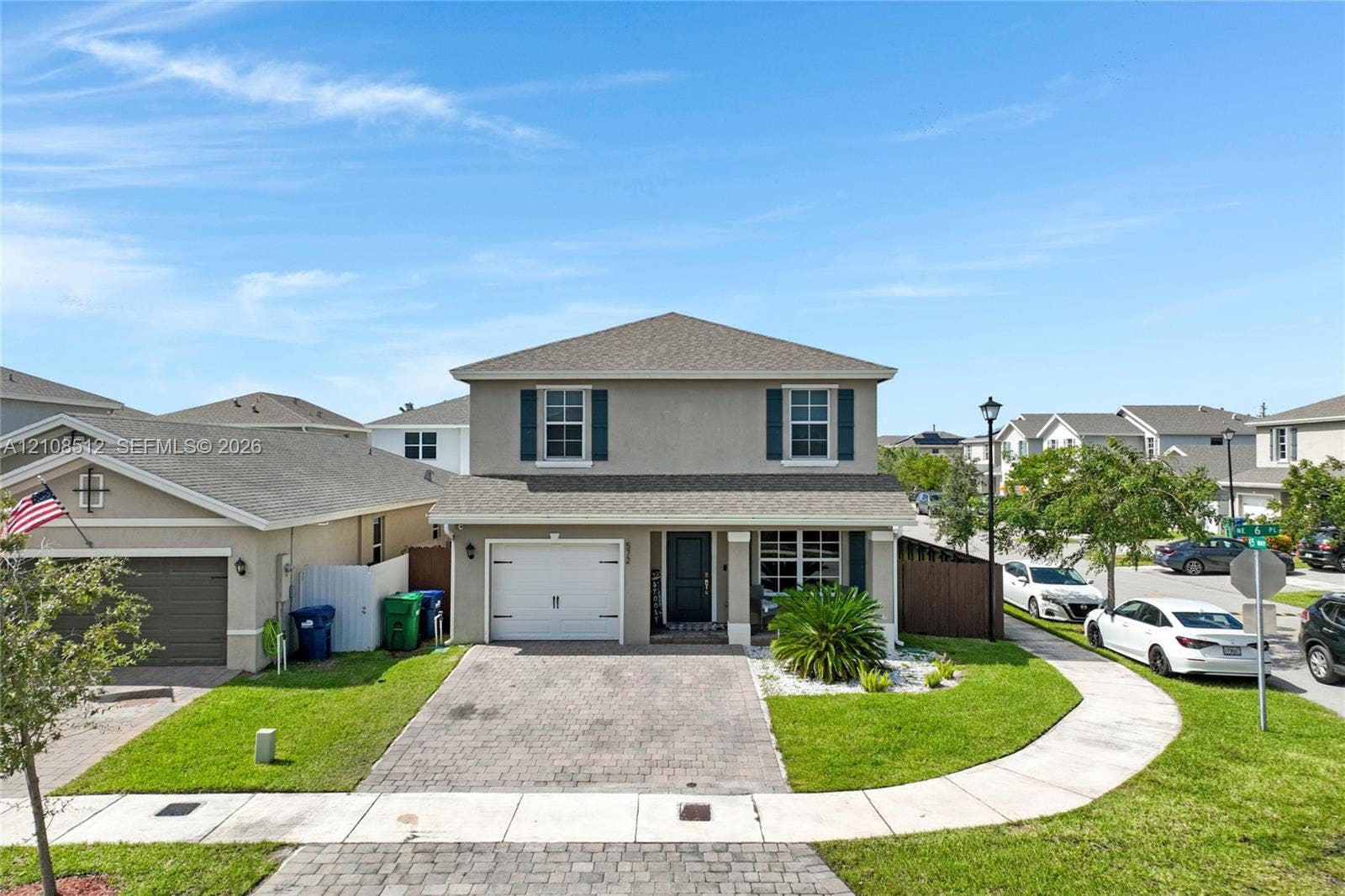 Two-story exterior featuring a stucco facade, paver driveway, single-car garage, and shuttered windows