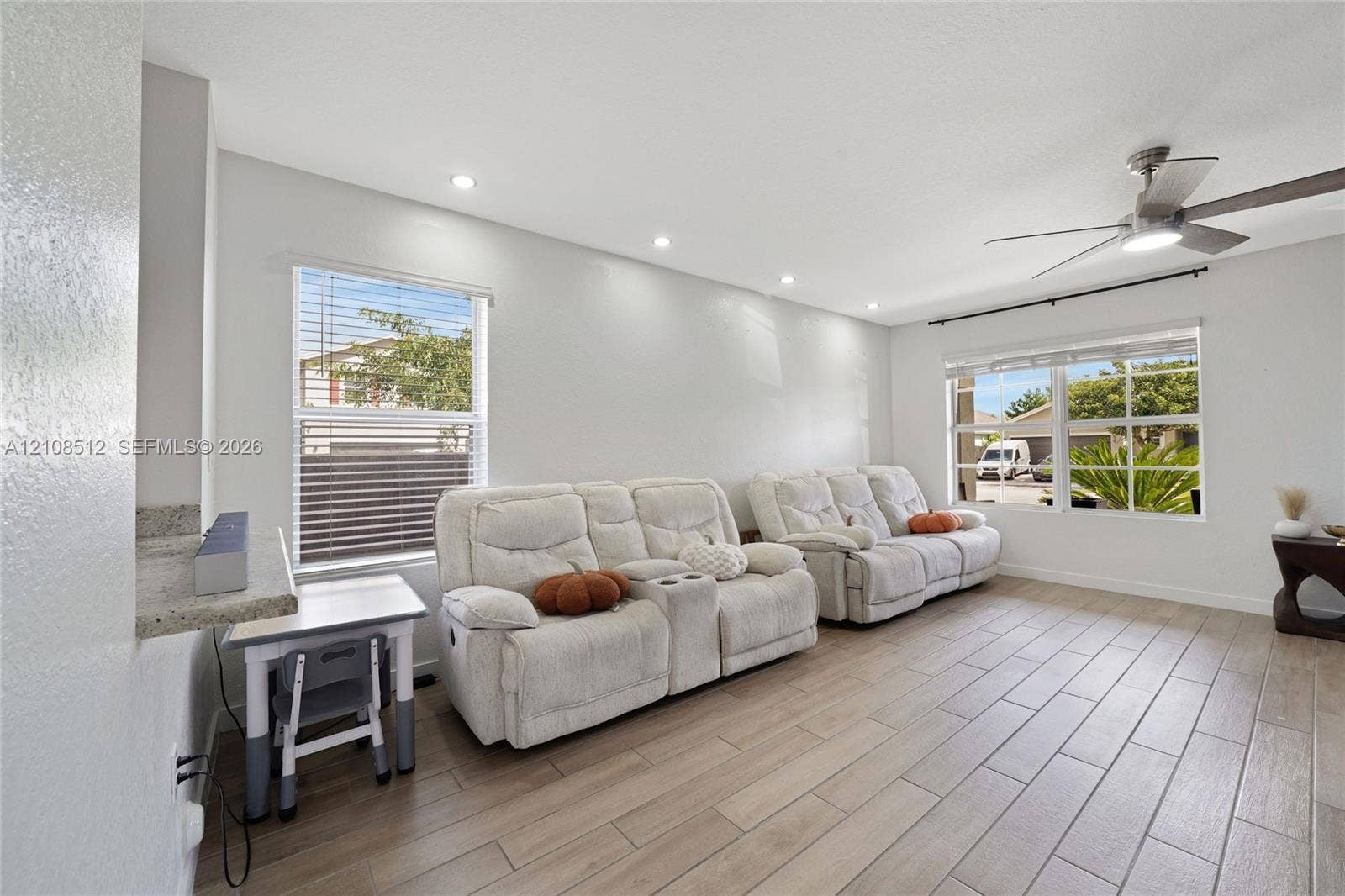 Wood-finish tile flooring, recessed ceiling lighting, ceiling fan with integrated light fixture, and dual windows with blinds