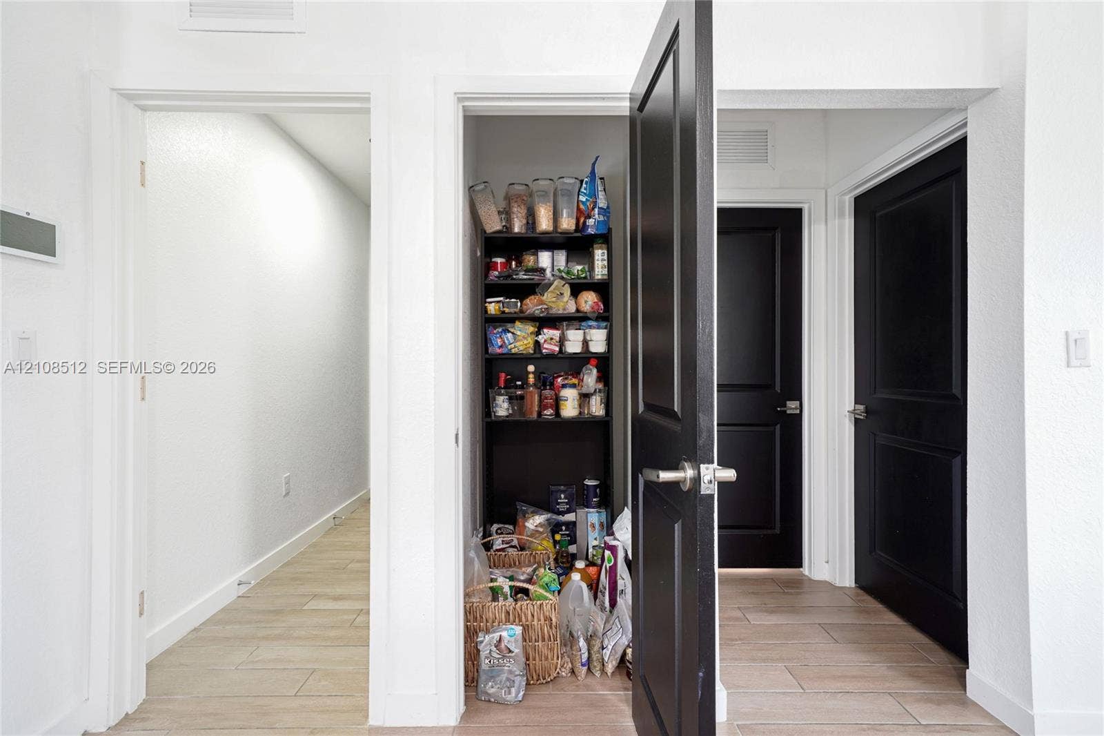 Interior space featuring wood-finish tile flooring, matte black solid-core doors with brushed nickel lever handles, and a dedicated built-in closet with integrated shelving