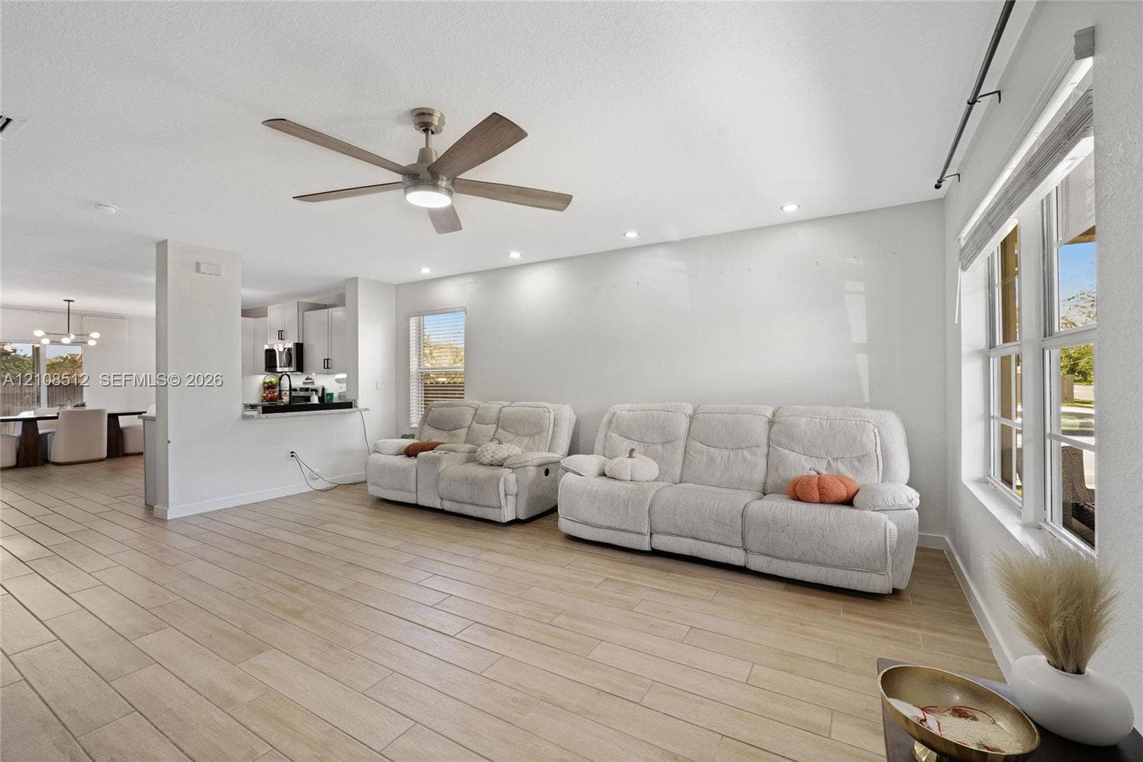 Open-concept area featuring wood-finish tile flooring, recessed lighting, a modern ceiling fan with integrated lighting, and expansive windows