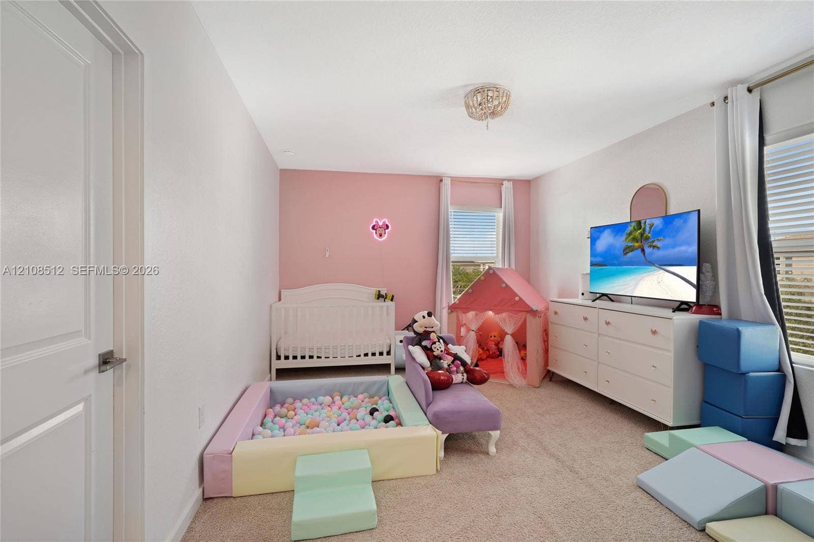 Neutral-toned carpeted room featuring an accent wall, two windows with horizontal blinds, and a circular ceiling-mounted light fixture