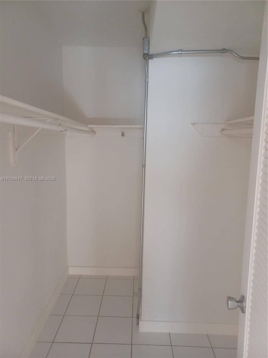 541 Blue Heron Drive, #204, Hallandale Beach, FL 33009 Storage area featuring white tile flooring, built-in metal shelving, and a louvered door