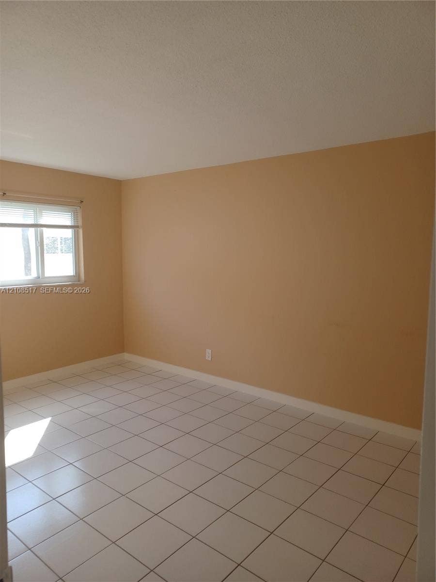 541 Blue Heron Drive, #204, Hallandale Beach, FL 33009 Interior space featuring neutral wall tones, white ceramic tile flooring, and a sliding glass window