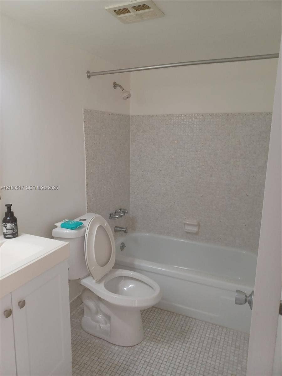 541 Blue Heron Drive, #204, Hallandale Beach, FL 33009 Bathroom featuring a white vanity cabinet with a countertop basin, a porcelain soaking tub, and tile wall surround with matching mosaic floor tiling