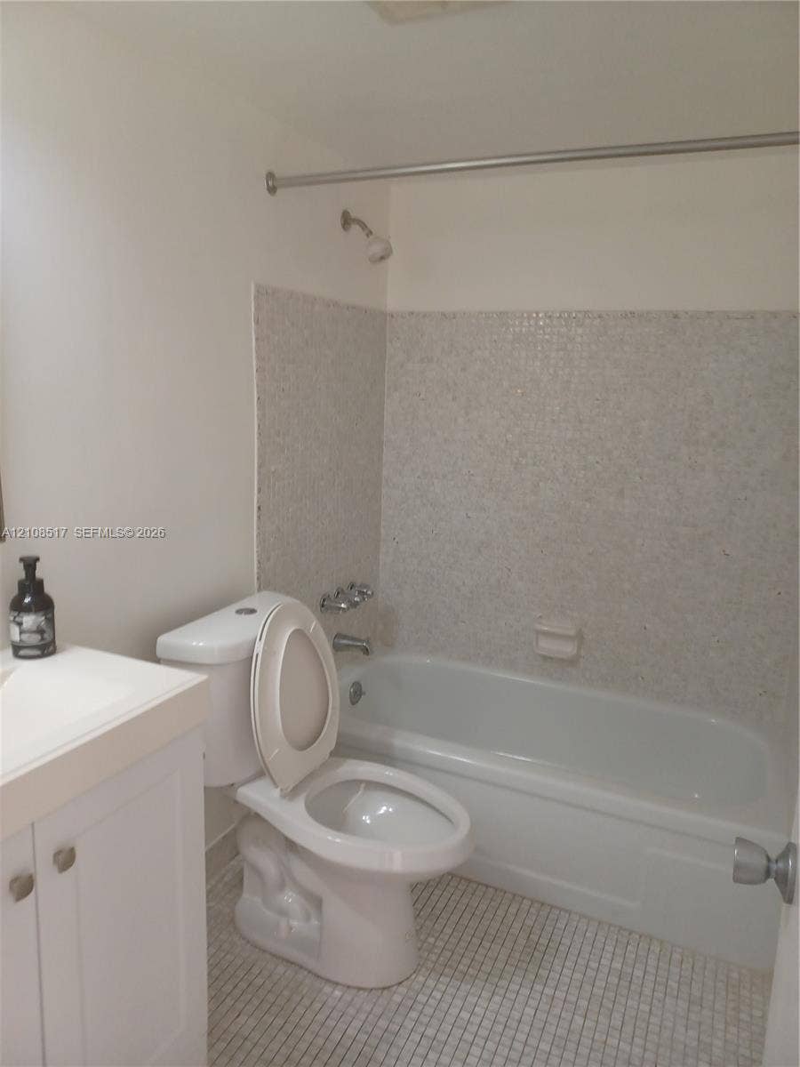 541 Blue Heron Drive, #204, Hallandale Beach, FL 33009 Bathroom featuring a porcelain tub with tile surround, a built-in vanity cabinet, and tiled flooring