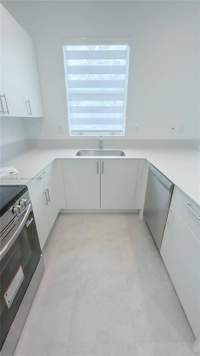 27733 SW 155th Court, #27733, Homestead, Homestead, FL 33032 Kitchen featuring white flat-panel cabinetry, light-toned stone-finish countertops, stainless steel appliances, a stainless steel undermount sink, and tile flooring