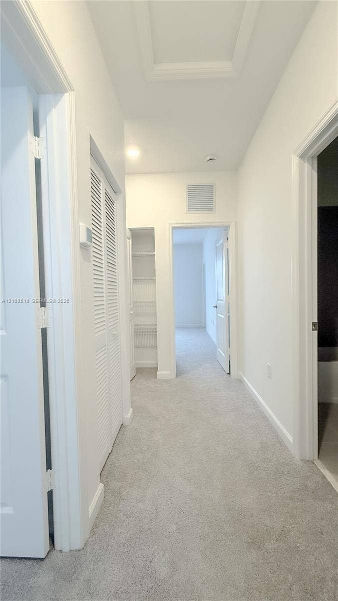27733 SW 155th Court, #27733, Homestead, Homestead, FL 33032 Interior corridor featuring wall-to-wall carpeting, louvered closet doors, and built-in shelving