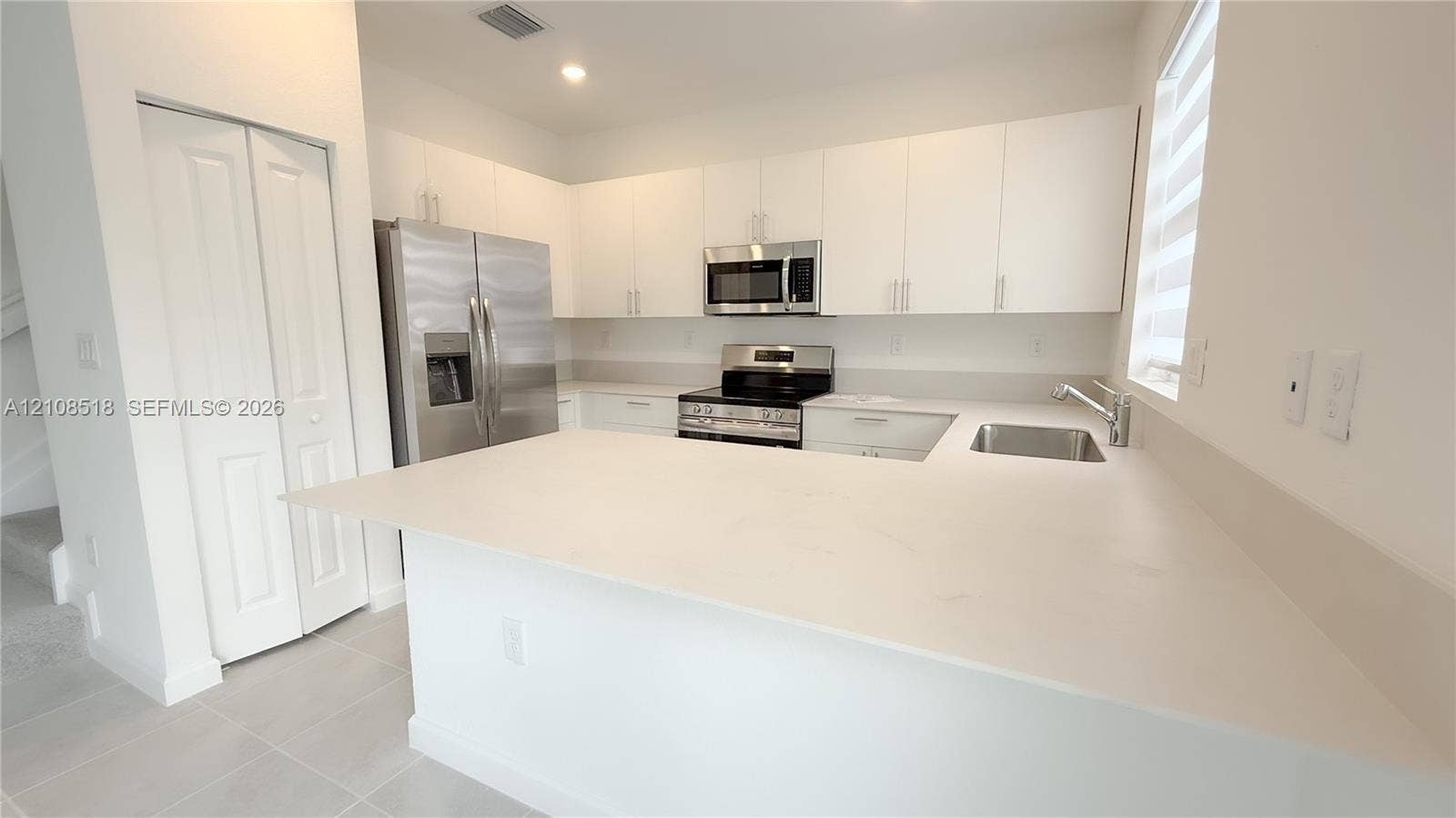 27733 SW 155th Court, #27733, Homestead, Homestead, FL 33032 Kitchen featuring white flat-panel cabinetry, quartz countertops, stainless steel appliances, and a peninsula with an integrated sink