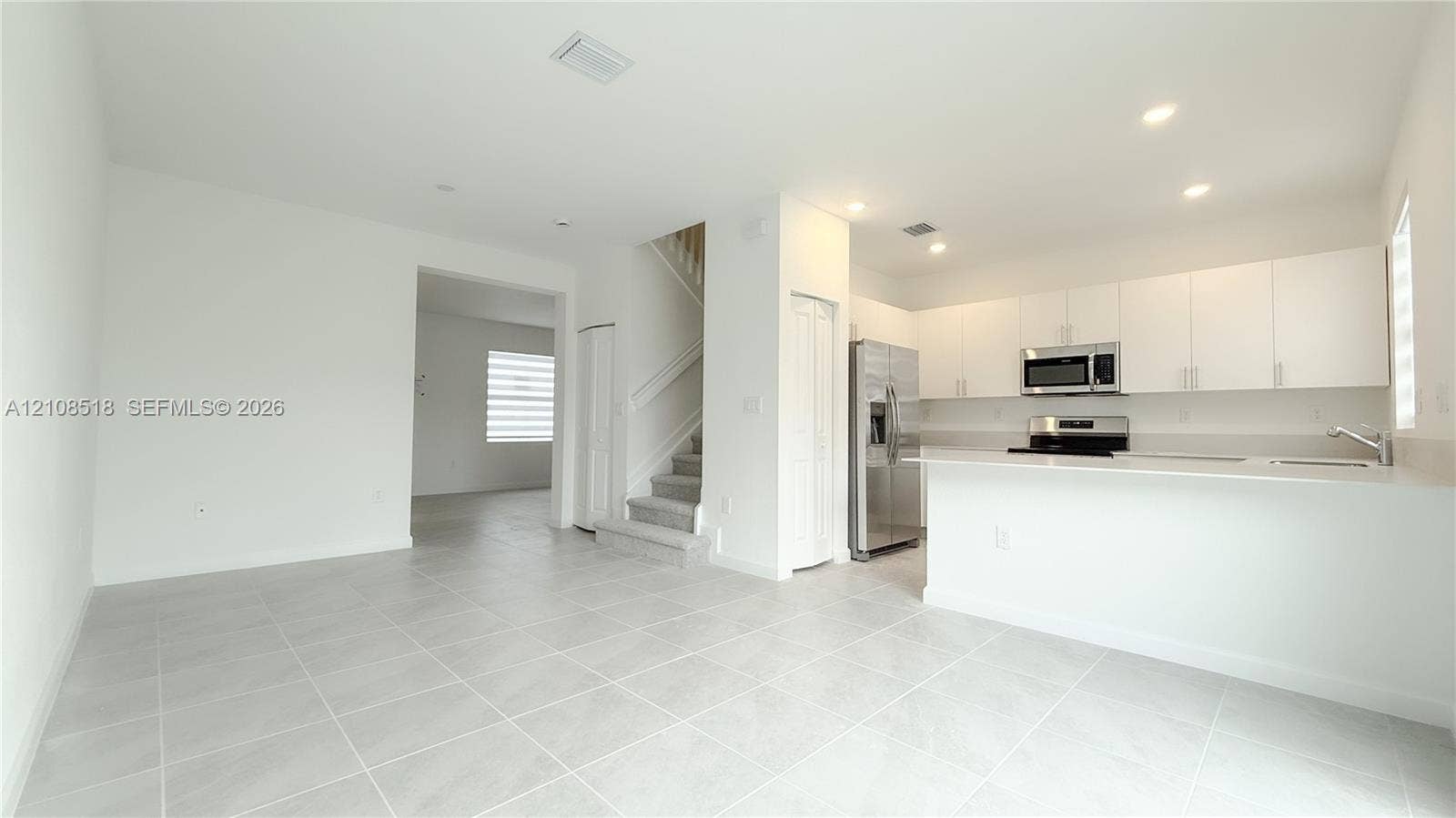 27733 SW 155th Court, #27733, Homestead, Homestead, FL 33032 Open-concept kitchen featuring flat-panel white cabinetry, quartz countertops, stainless steel appliances, and large-format tile flooring