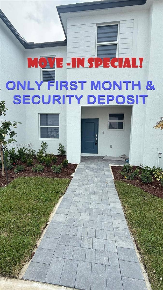 27733 SW 155th Court, #27733, Homestead, Homestead, FL 33032 Two-story exterior featuring white stucco siding, a recessed entryway with a solid door, and a paved stone walkway