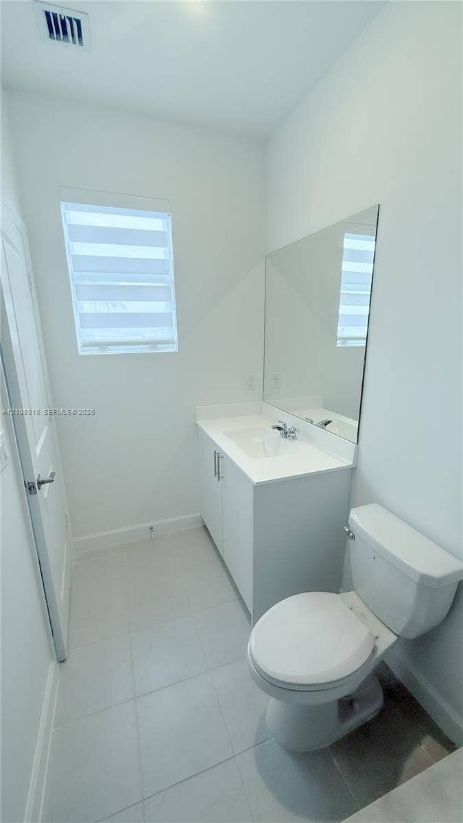 27733 SW 155th Court, #27733, Homestead, Homestead, FL 33032 White vanity with an integrated countertop, large rectangular wall-mounted mirror, ceramic tile flooring, and layered light-filtering window treatments