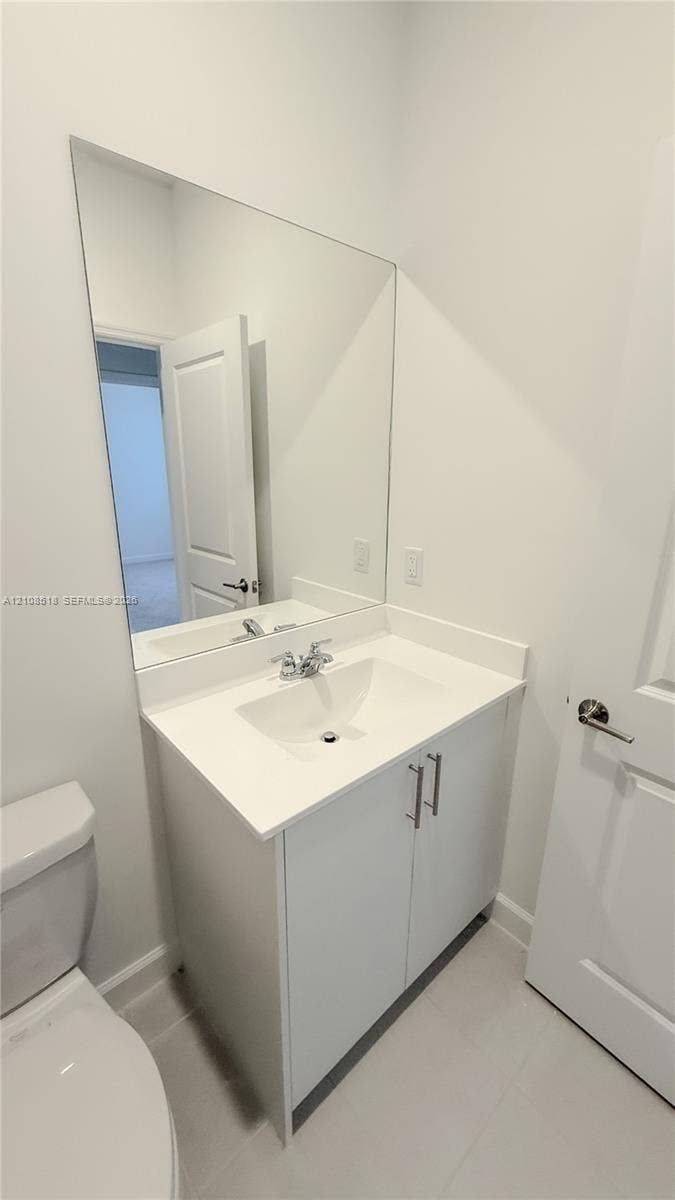 27733 SW 155th Court, #27733, Homestead, Homestead, FL 33032 White vanity cabinet with a solid surface countertop, integrated sink, chrome dual-handle faucet, and full-length vanity mirror