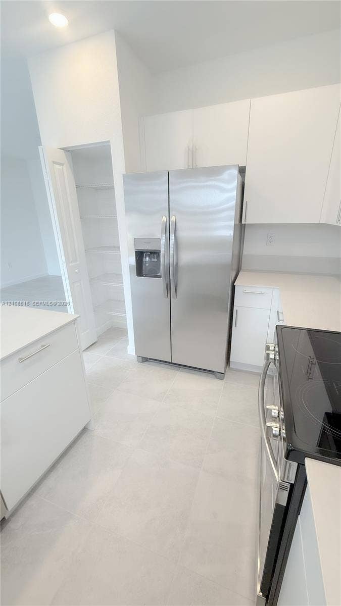 27733 SW 155th Court, #27733, Homestead, Homestead, FL 33032 Kitchen featuring white cabinetry, light-toned stone-finish countertops, stainless steel appliances, and a walk-in pantry with built-in shelving