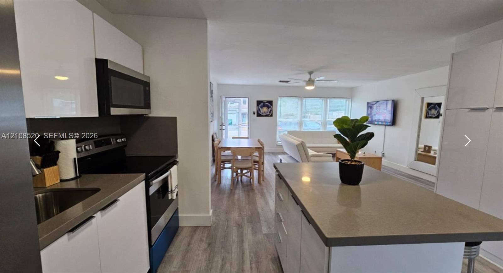 4536 SW 24th Avenue, Dania, Dania Beach, FL 33312 Kitchen featuring white gloss cabinetry, stone-finish countertops, stainless steel appliances, a central island, and wood-finish flooring