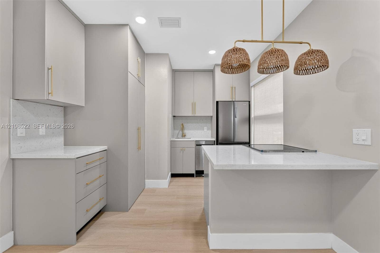 Kitchen featuring flat-panel cabinetry with gold-tone hardware, stone-surface countertops, wood-finish flooring, and a multi-pendant woven light fixture