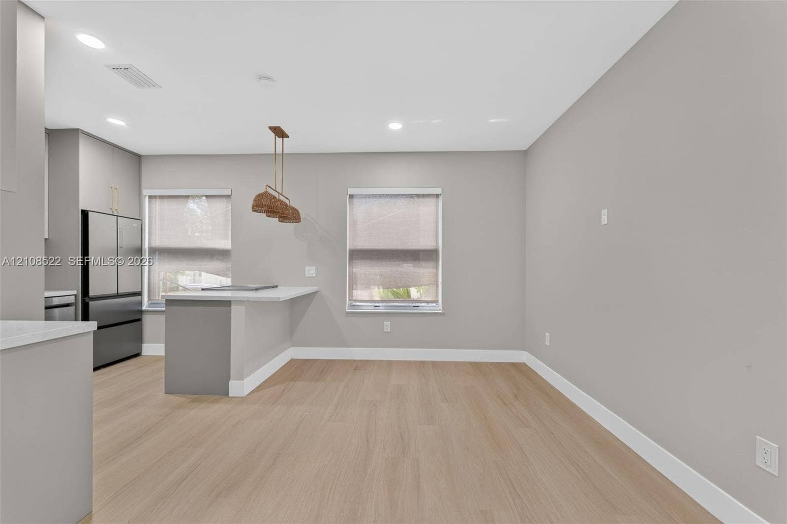 Kitchen featuring wood-finish flooring, a quartz-topped peninsula, recessed lighting, and stainless steel appliances