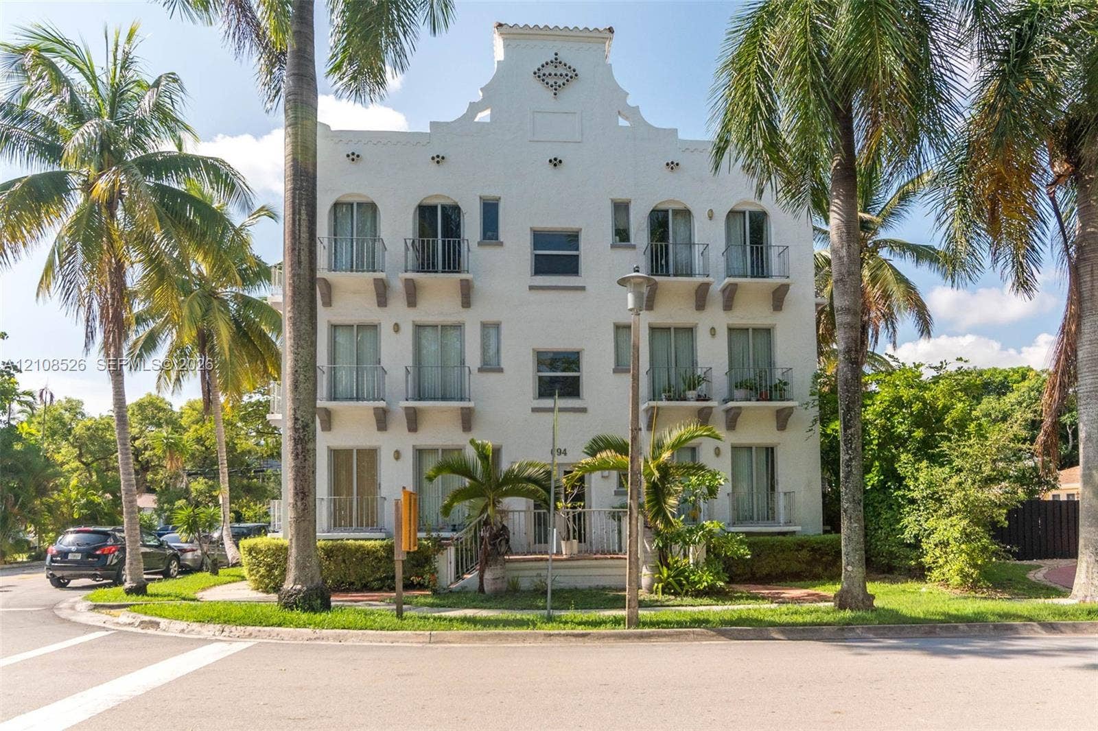 Multi-story exterior featuring a decorative parapet, stucco facade, and metal-railing balconies