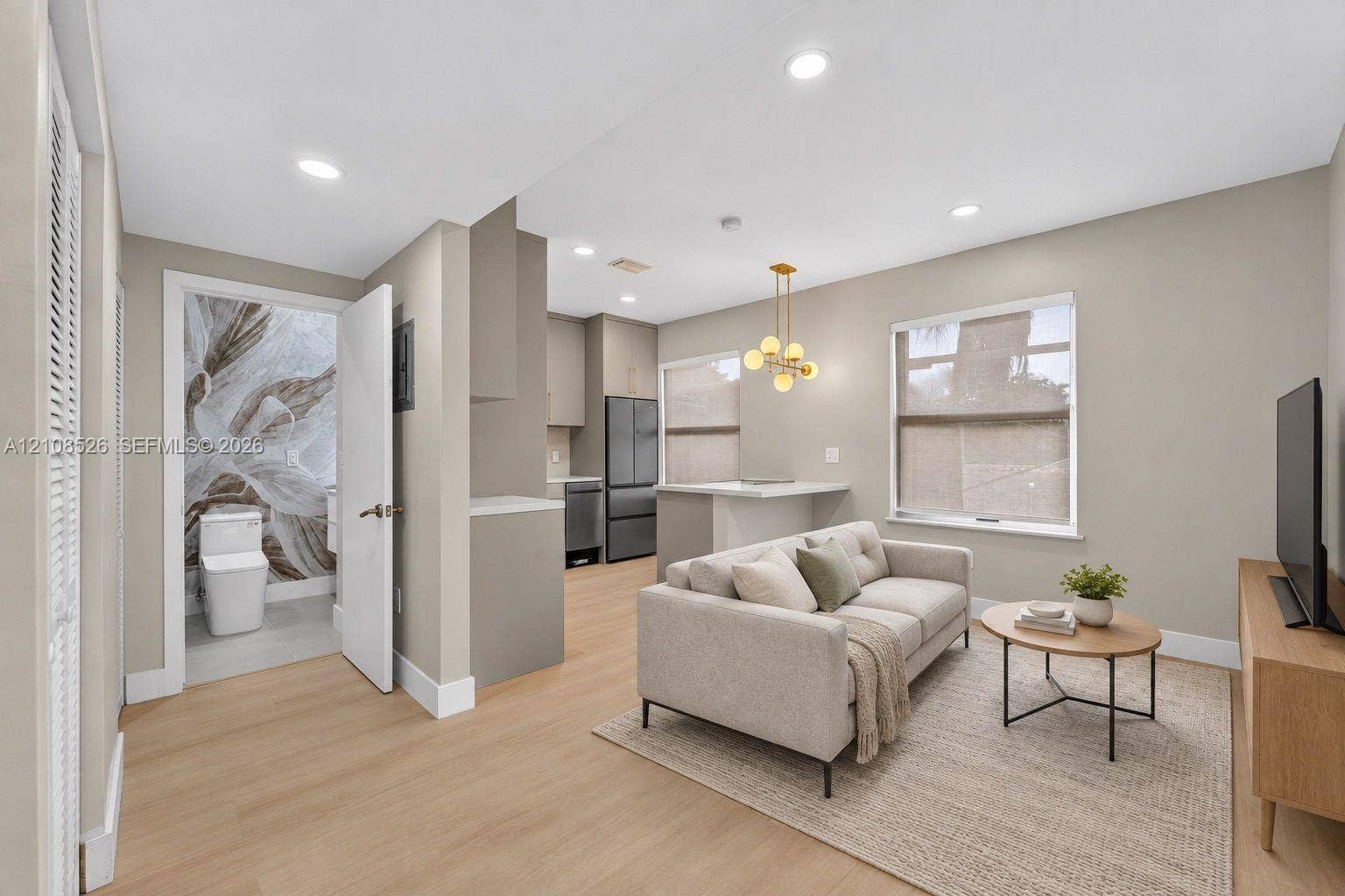 Open-concept interior featuring light wood-finish flooring, recessed lighting, and a modern kitchen with stainless steel appliances