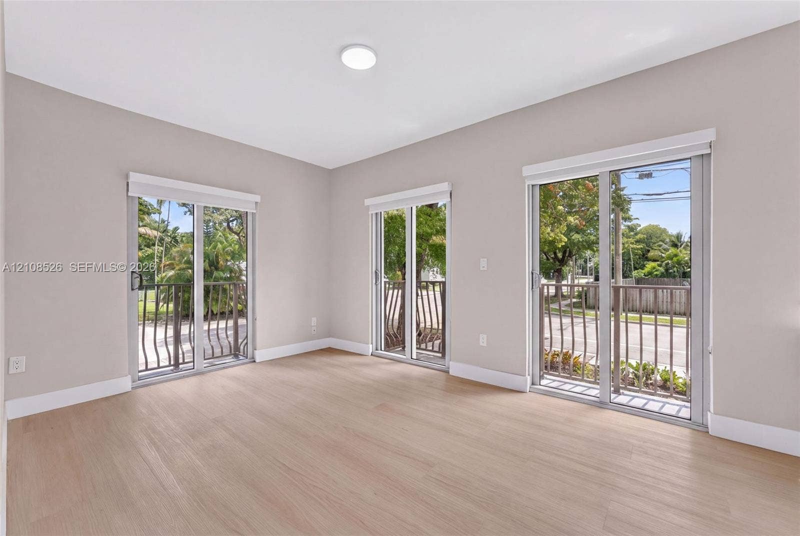 Neutral-toned interior featuring wood-finish flooring, three sliding glass doors, and metal railings