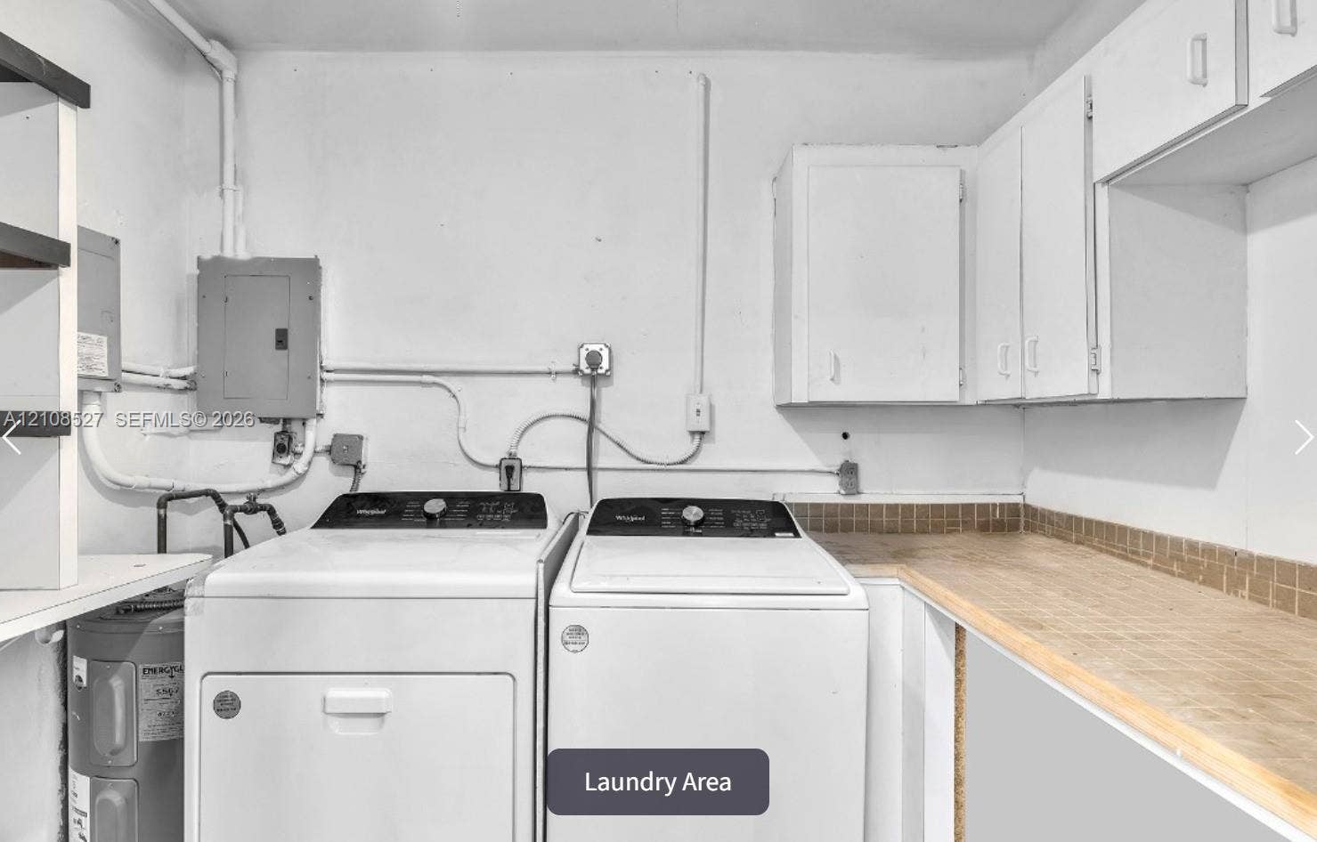 4549 SW 24th Avenue, Dania, Dania Beach, FL 33312 Laundry space featuring built-in white cabinetry, expansive wood-tone countertop, and tiled backsplash