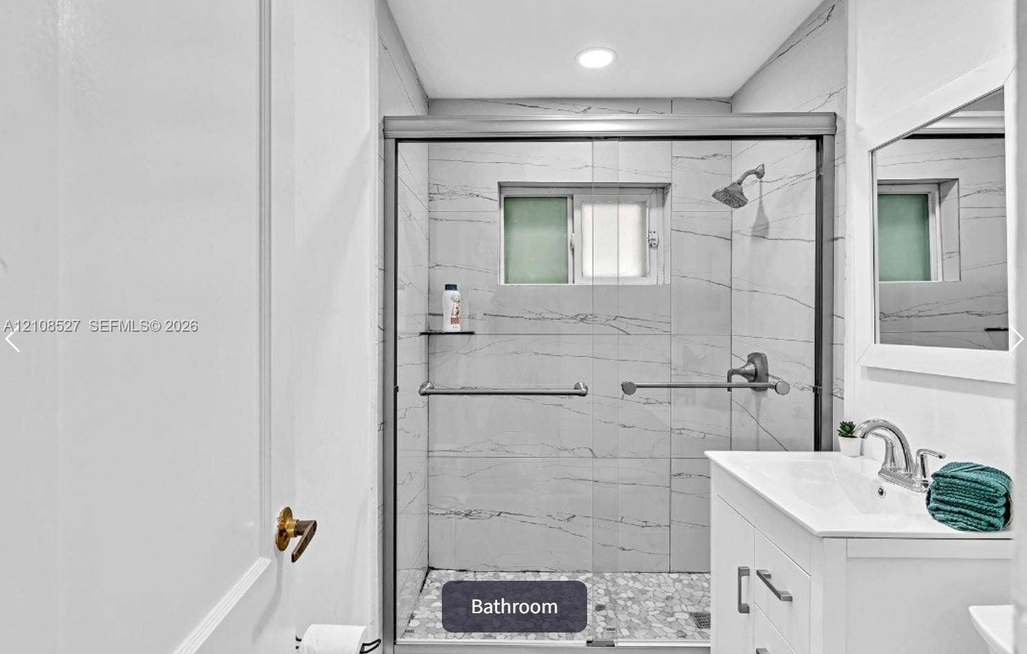 4549 SW 24th Avenue, Dania, Dania Beach, FL 33312 Bathroom featuring a walk-in shower with stone-patterned wall tile, a glass sliding enclosure, pebble-tile flooring, and a white vanity with a polished metal faucet
