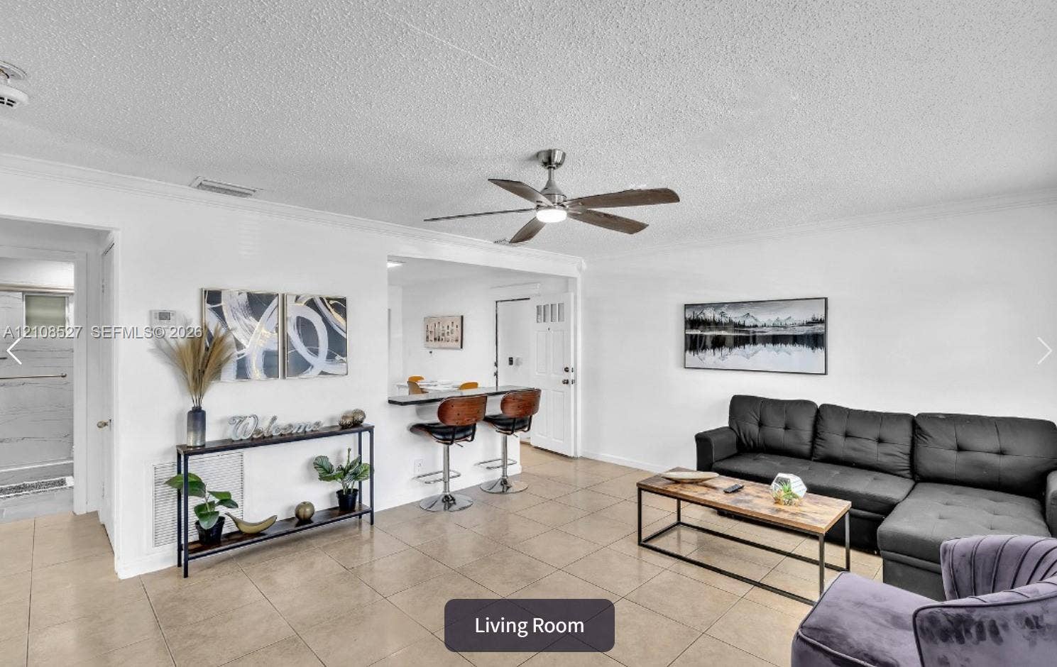4549 SW 24th Avenue, Dania, Dania Beach, FL 33312 Open living area featuring large-format ceramic tile flooring, a neutral color palette, a brushed nickel ceiling fan, and a breakfast bar