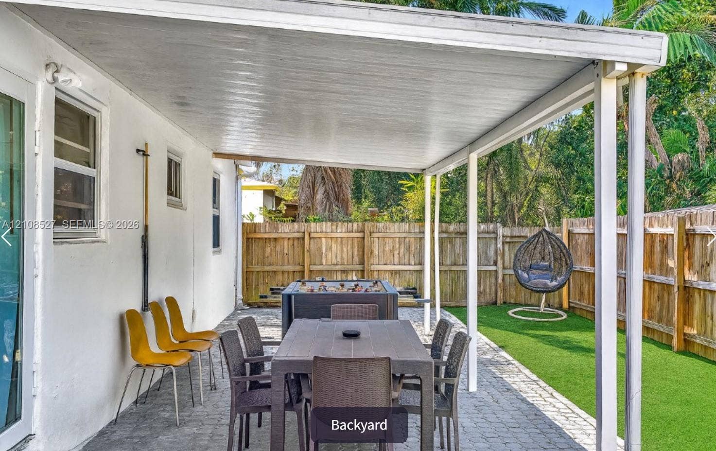 4549 SW 24th Avenue, Dania, Dania Beach, FL 33312 Covered outdoor patio with paver flooring, synthetic turf lawn, and wood privacy fencing