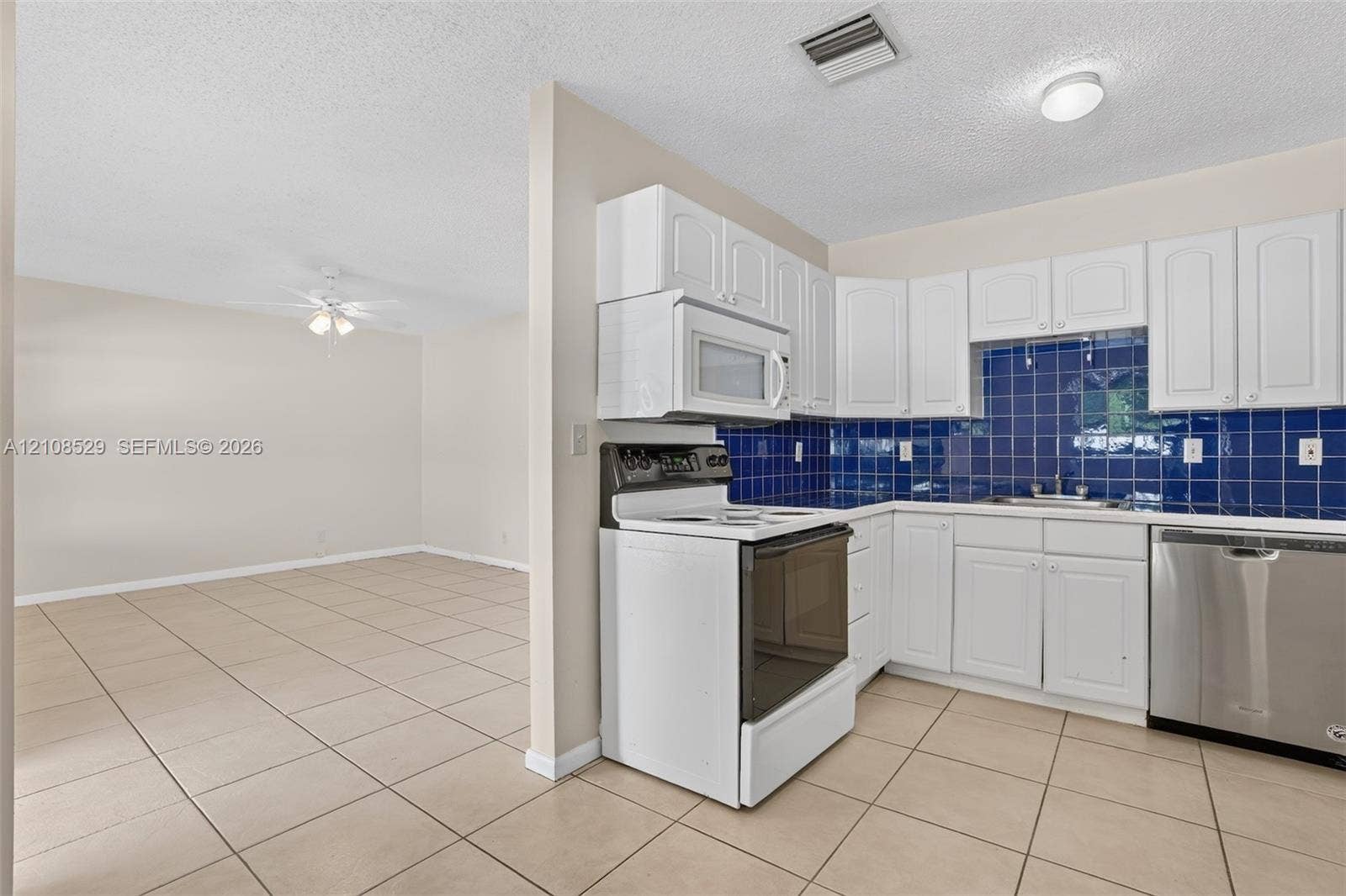 1015 SW 4th Avenue, #A, Fort Lauderdale, Fort Lauderdale, FL 33315 Kitchen featuring white cabinetry, blue tiled backsplash, stainless steel dishwasher, built-in microwave, and tile flooring