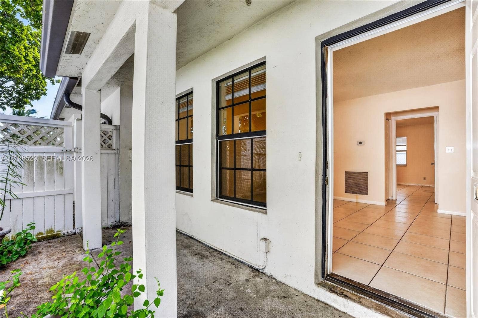 1015 SW 4th Avenue, #A, Fort Lauderdale, Fort Lauderdale, FL 33315 Covered exterior patio featuring a concrete floor, white structural columns, grid-patterned windows, and a white privacy fence