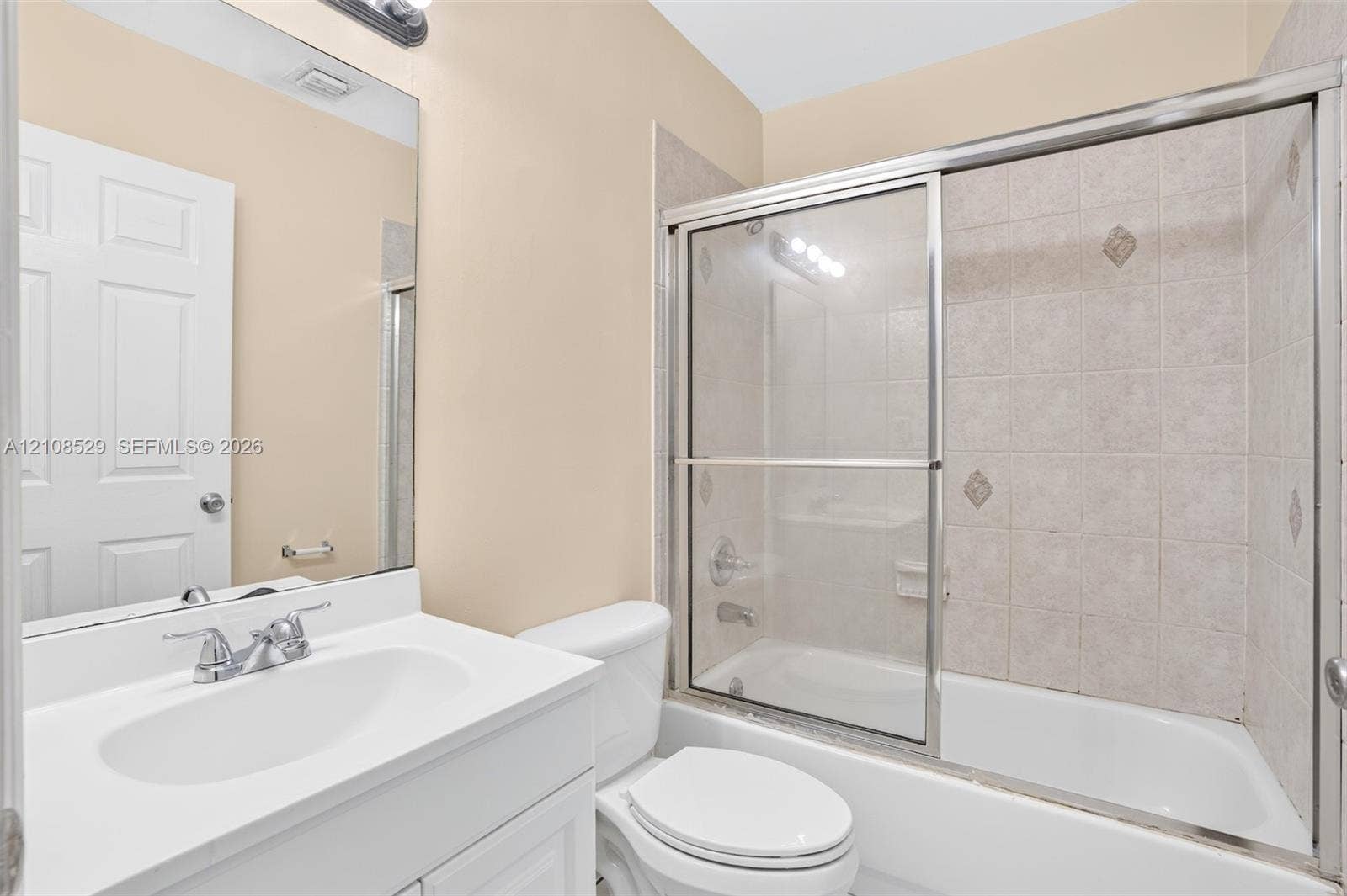 1015 SW 4th Avenue, #A, Fort Lauderdale, Fort Lauderdale, FL 33315 Bathroom featuring a white vanity cabinet, solid-surface countertop with an integrated sink, polished chrome faucet, and a shower-tub combination with sliding glass doors and tiled surround