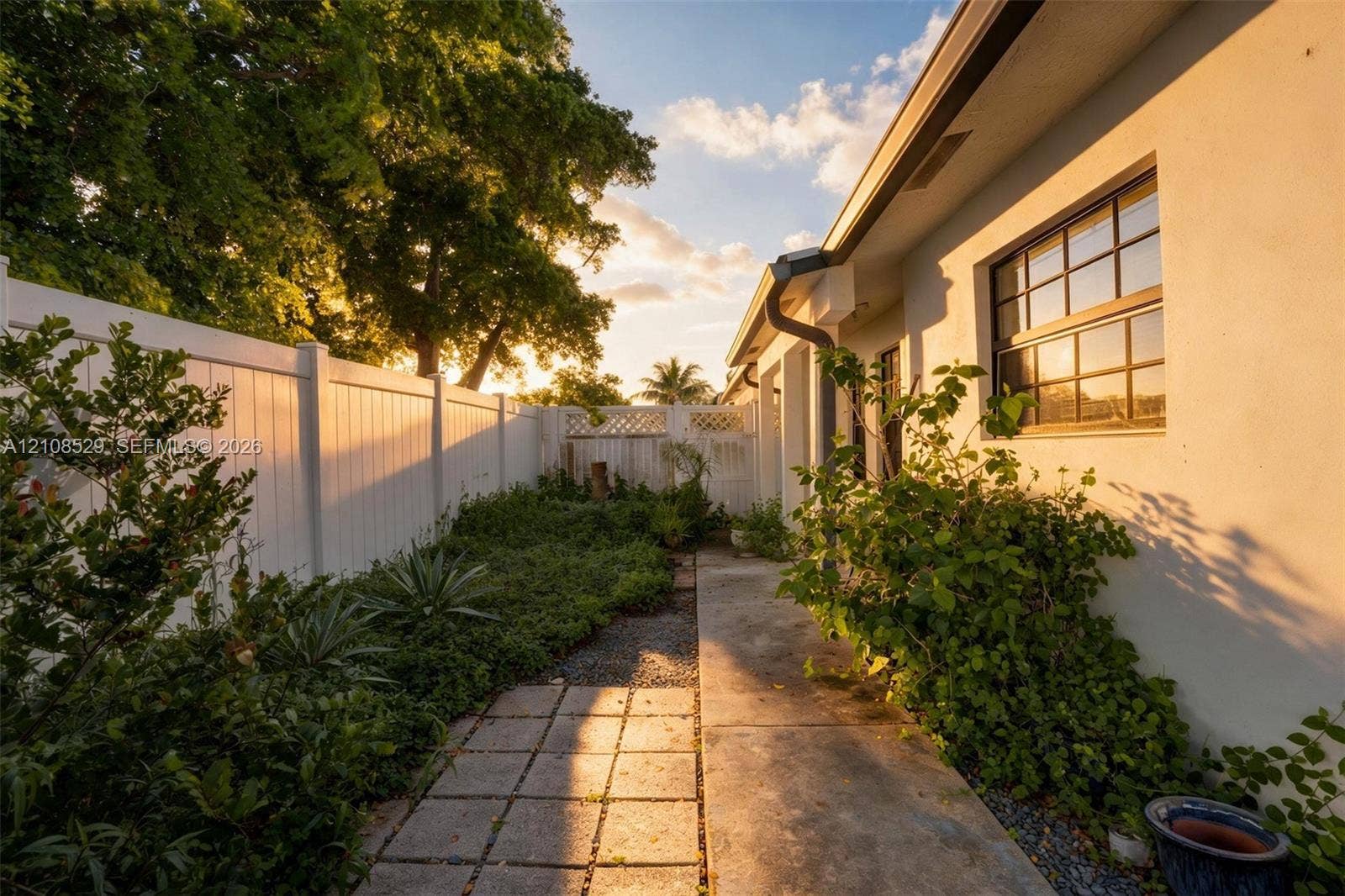 1015 SW 4th Avenue, #A, Fort Lauderdale, Fort Lauderdale, FL 33315 Exterior side yard featuring a concrete paver path, solid vinyl privacy fencing with lattice accents, multi-pane windows, and stucco siding