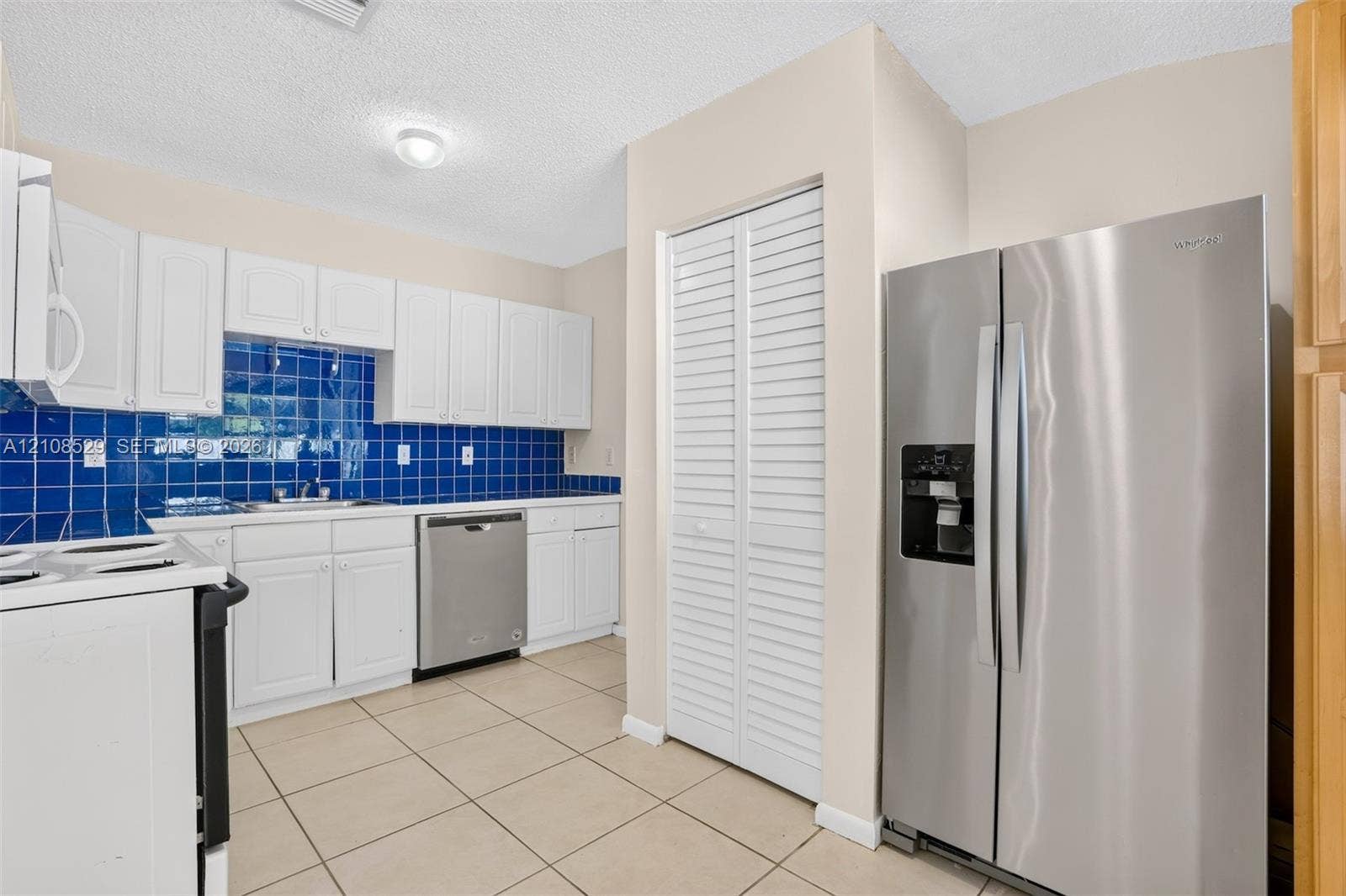 1015 SW 4th Avenue, #A, Fort Lauderdale, Fort Lauderdale, FL 33315 Kitchen featuring white cabinetry, blue tiled backsplash, stainless steel appliances, tile flooring, and a louvered pantry door