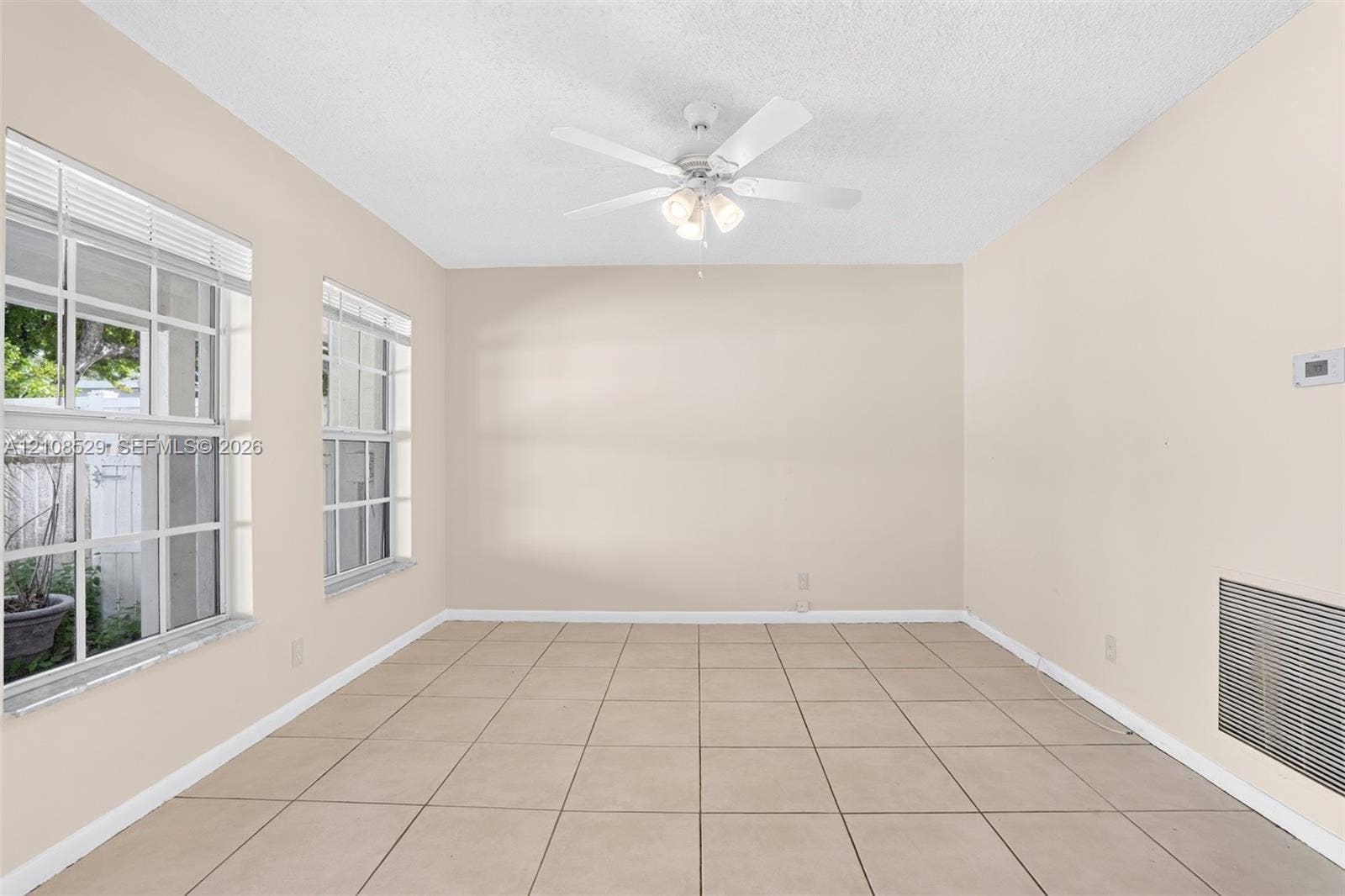 1015 SW 4th Avenue, #A, Fort Lauderdale, Fort Lauderdale, FL 33315 Interior space featuring large-format neutral floor tile, dual grid-pattern windows, and a ceiling-mounted light fixture with a multi-blade fan