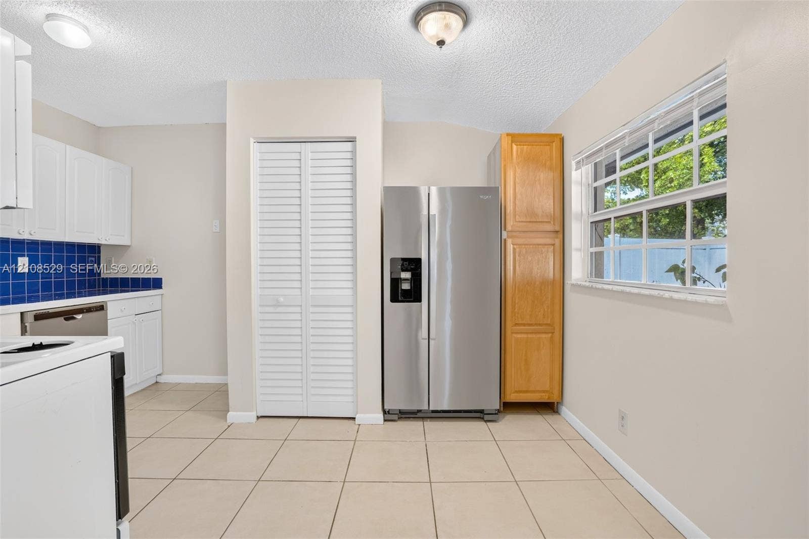 1015 SW 4th Avenue, #A, Fort Lauderdale, Fort Lauderdale, FL 33315 Kitchen featuring white cabinetry, blue tiled backsplash, stainless steel refrigerator, louvered closet doors, and ceramic tile flooring