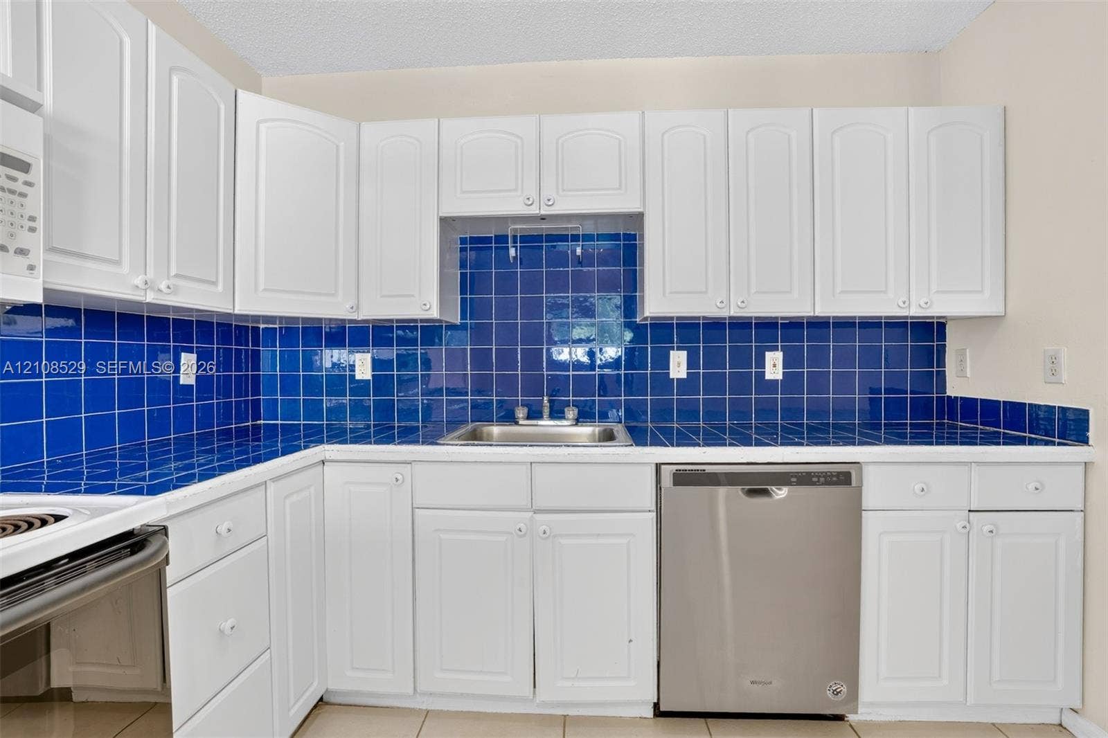 1015 SW 4th Avenue, #A, Fort Lauderdale, Fort Lauderdale, FL 33315 Kitchen featuring white shaker-style cabinetry, a deep blue tiled backsplash, coordinating tile countertops, and a stainless steel dishwasher