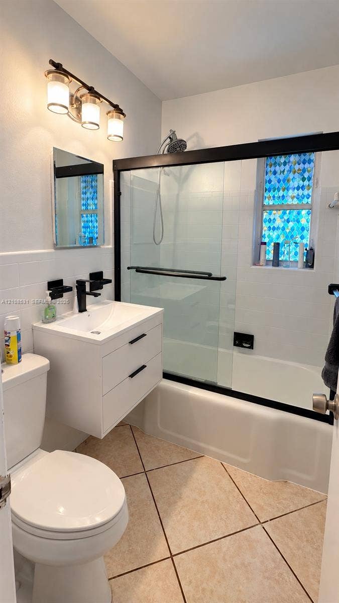 3024 Clyde Road, #1, West Palm Beach, West Palm Beach, FL 33405 Floating white vanity with a rectangular sink, matte black faucet, wall-mounted three-light fixture, and sliding glass shower door with a black frame
