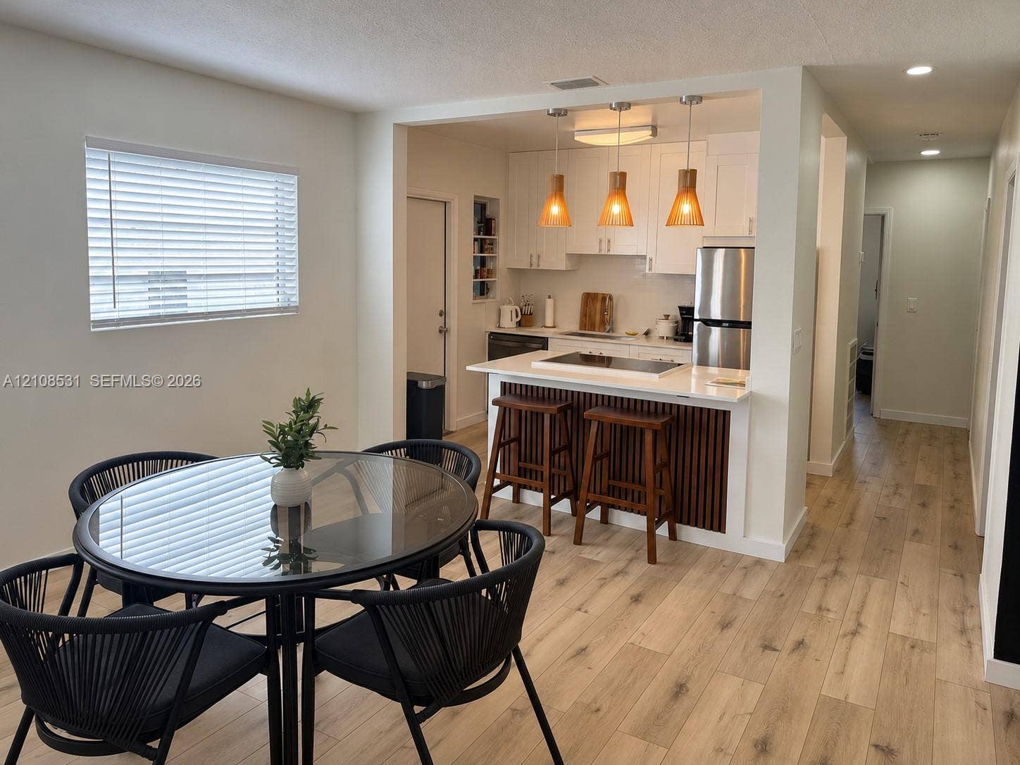 3024 Clyde Road, #1, West Palm Beach, West Palm Beach, FL 33405 Kitchen featuring white shaker-style cabinetry, wood-slat peninsula detailing, quartz-surface countertops, stainless steel appliances, and wood-finish flooring throughout