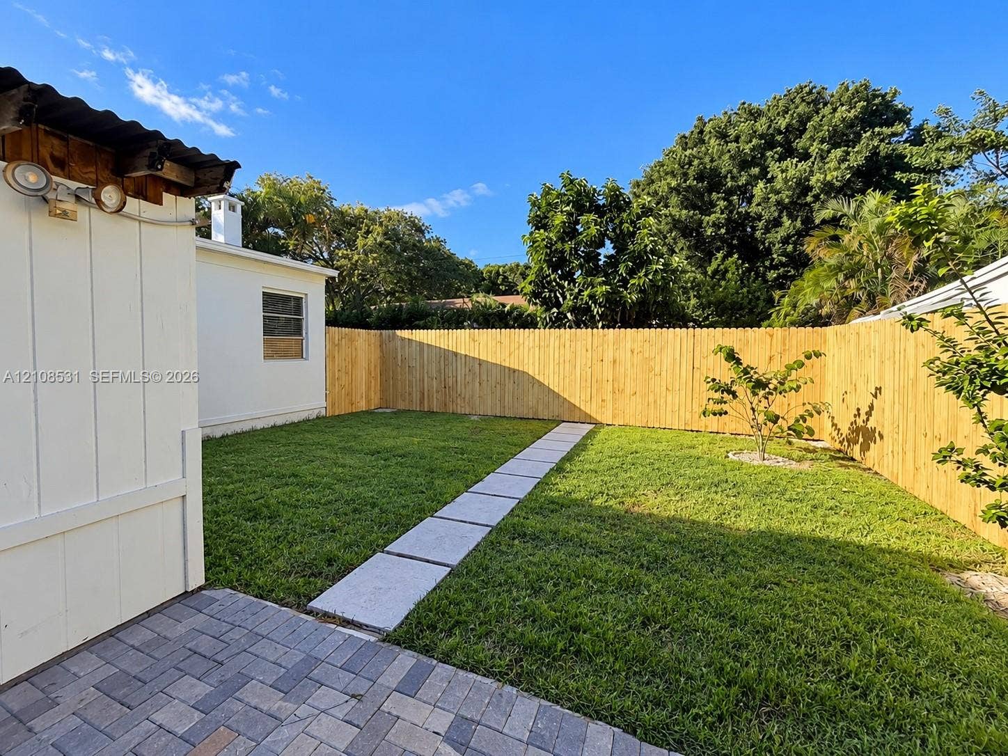 3024 Clyde Road, #1, West Palm Beach, West Palm Beach, FL 33405 Private fenced yard featuring a brick paver patio, stone-finish walkway, and manicured lawn