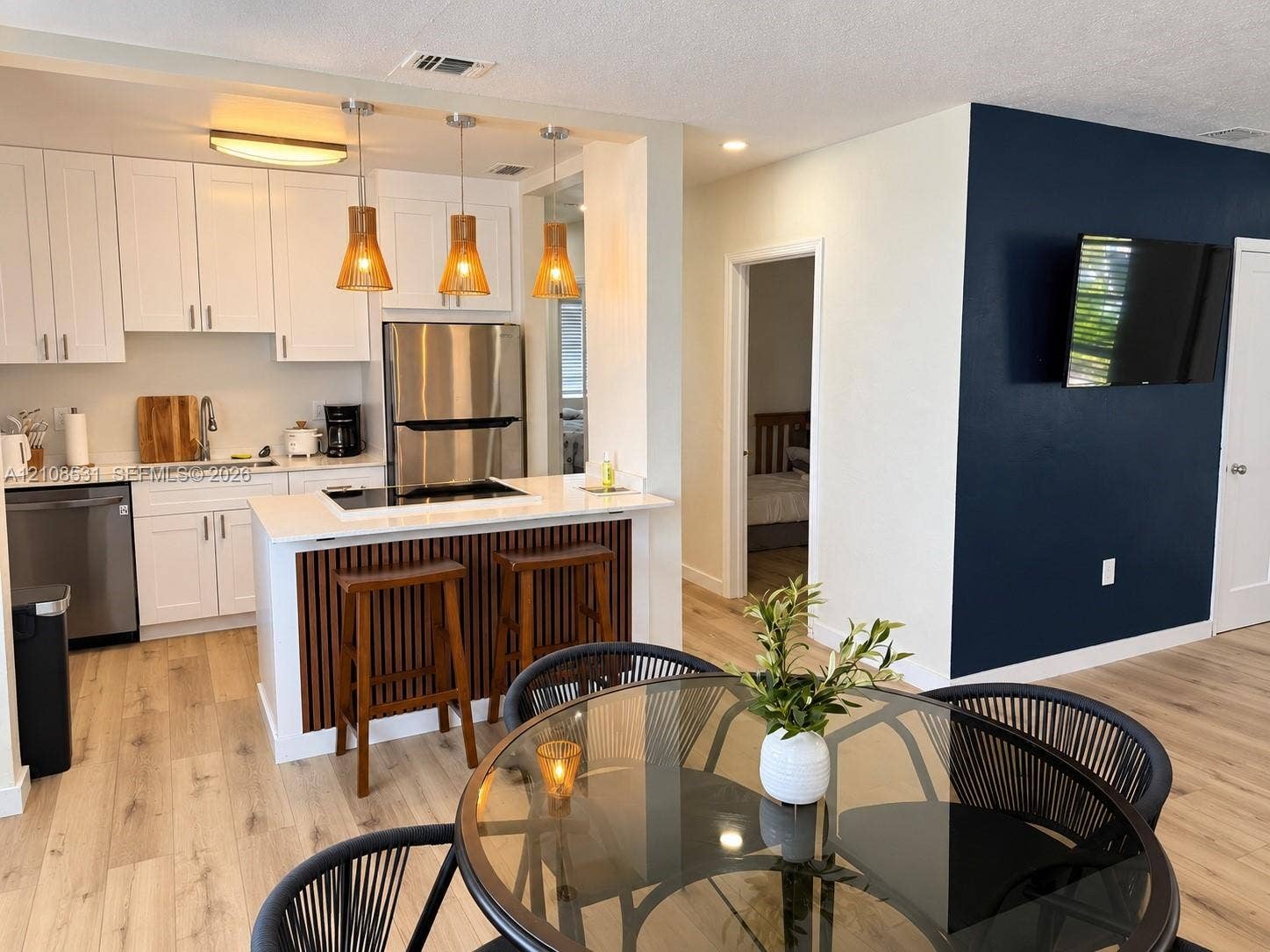3024 Clyde Road, #1, West Palm Beach, West Palm Beach, FL 33405 Kitchen featuring white cabinetry, quartz-surface countertops, stainless steel appliances, and a wood-slat breakfast bar accented by hanging pendant lighting