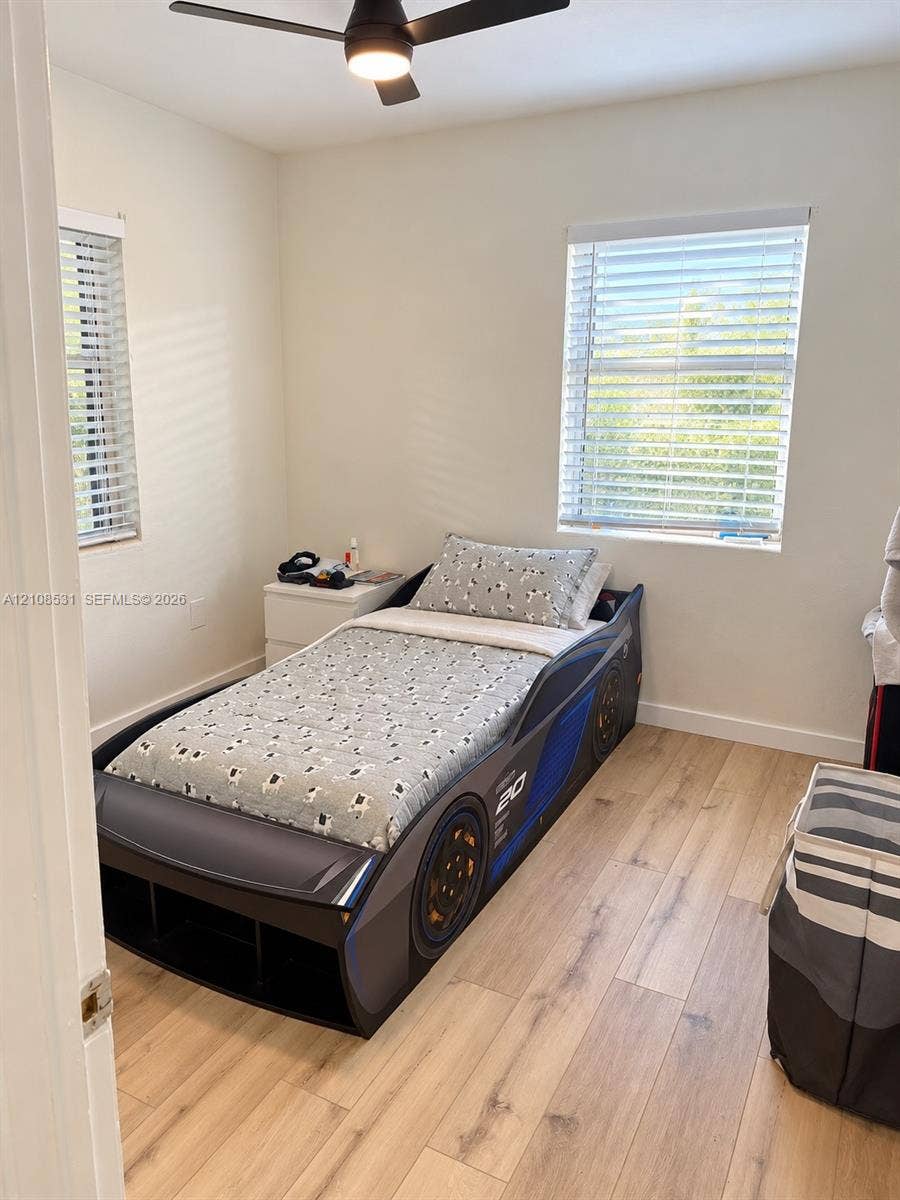 3024 Clyde Road, #1, West Palm Beach, West Palm Beach, FL 33405 Room featuring wood-finish flooring, dual windows with horizontal blinds, and an integrated ceiling fan with light fixture