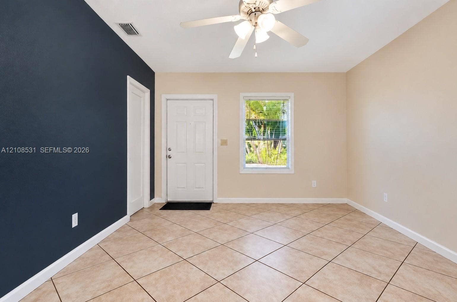3024 Clyde Road, #1, West Palm Beach, West Palm Beach, FL 33405 Room featuring diagonal tile flooring, a dark accent wall, a solid entry door, and a ceiling-mounted light fixture with integrated fan