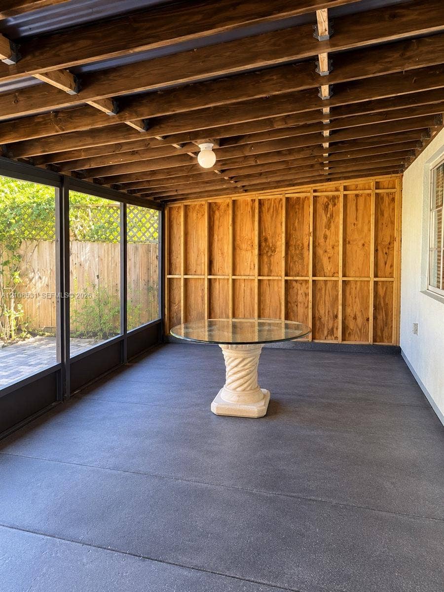 3024 Clyde Road, #1, West Palm Beach, West Palm Beach, FL 33405 Enclosed porch featuring an exposed wood-beam ceiling, concrete flooring, and screen wall panels