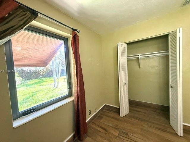 1124 NE 7th Street, Hallandale Beach, Hallandale Beach, FL 33009 Wood-finish flooring, metal-frame casement window with tile sill, and closet featuring white louvered doors