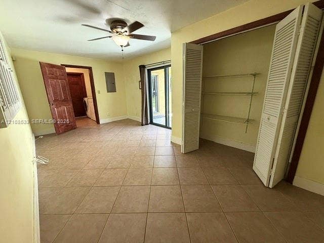 1124 NE 7th Street, Hallandale Beach, Hallandale Beach, FL 33009 Room featuring square ceramic tile flooring, a ceiling fan with integrated lighting, bi-fold louvered closet doors with adjustable shelving, and a glass sliding door